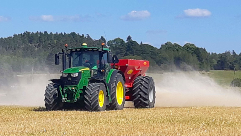 Traktori levittää kalkkia pellolla