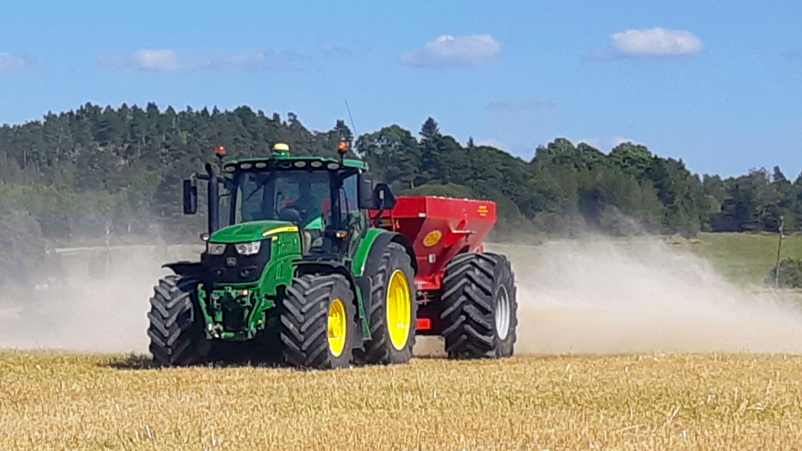 Traktori levittää kalkkia pellolla